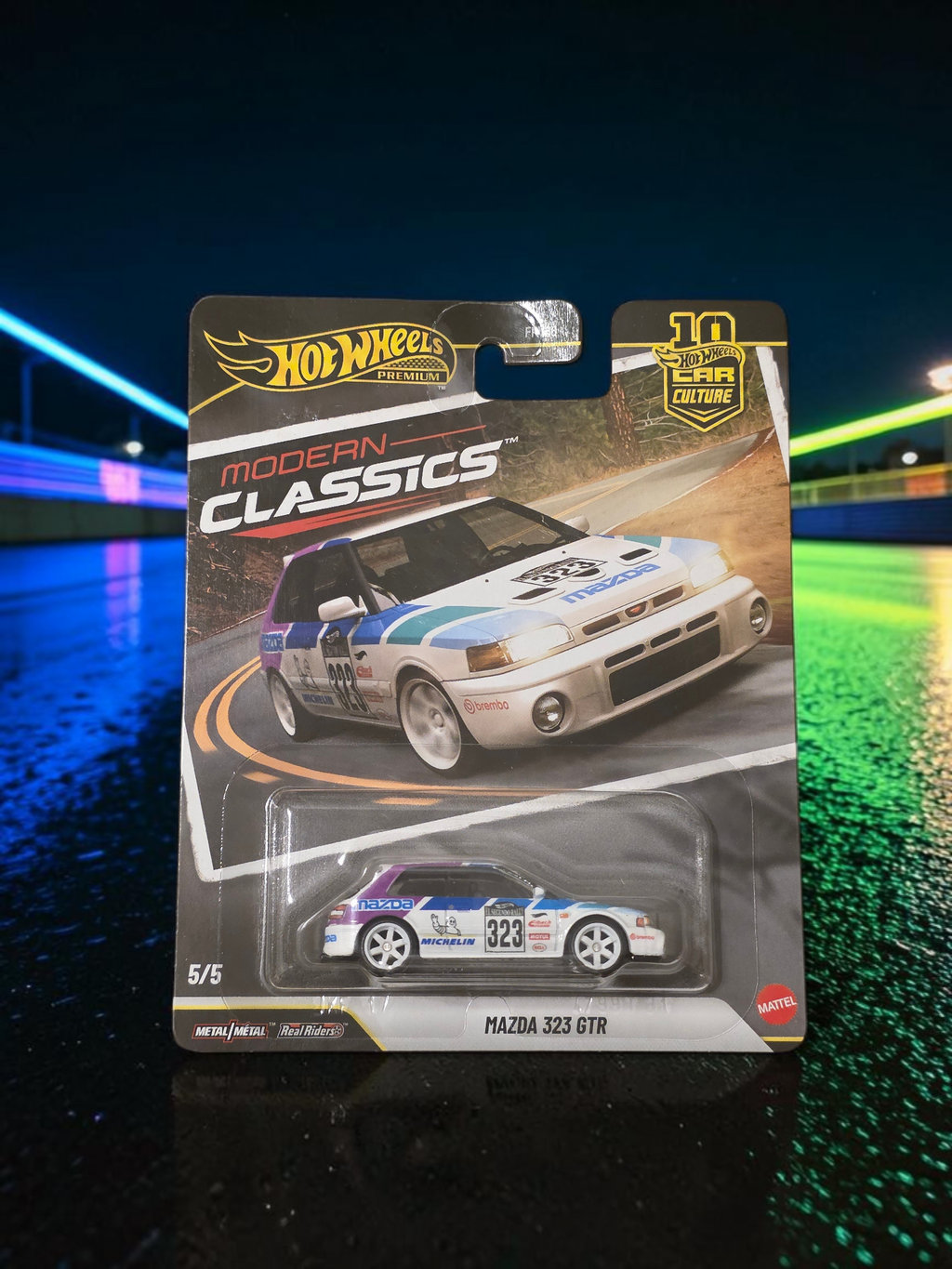 Winters & Johnson Diecast Hot Wheels Mazda 323 GTR Modern Classics premium diecast car in white, blue, and purple.